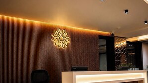 Moderni vastaanottotiski, jossa on puupaneelista tehty etuosa, seinässä logo ja vastaanottoalue, jossa on tietokone ja kasvi.