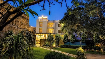 A hotel with a well-maintained garden, a visible entrance, and a sign indicating the hotel's name.