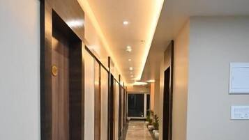 A long, narrow hallway with a polished marble floor, recessed lighting, and doors on both sides.