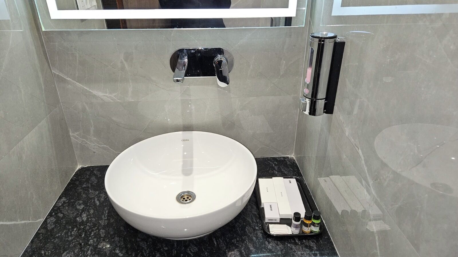 A bathroom with a white sink, a black faucet, and a black marble countertop.