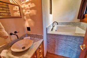 Une salle de bain avec un lavabo en marbre, une baignoire et une porte en bois.