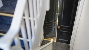 A black door with a brass doorknob, a white door frame, and a carpeted stair landing. - Aldwark Mews (York)