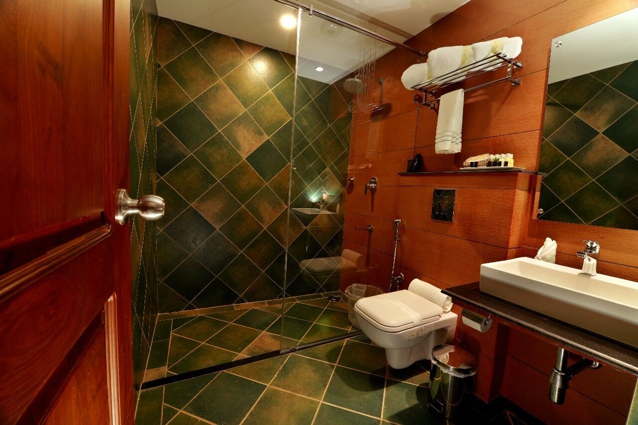 A bathroom with a shower, toilet, sink, and a mirror.