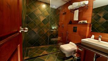 A bathroom with a shower, toilet, sink, and a mirror.