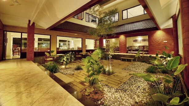 Un amplio patio interior con zona de estar central, rodeado de muros de ladrillo y grandes ventanales.