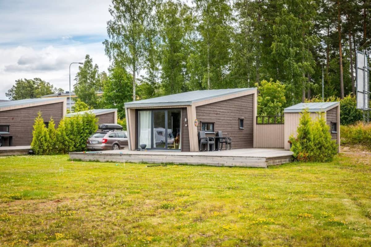 Un hébergement moderne de type « camping-car », doté d’un patio couvert, d’un abri pour voiture et d’une pelouse.
