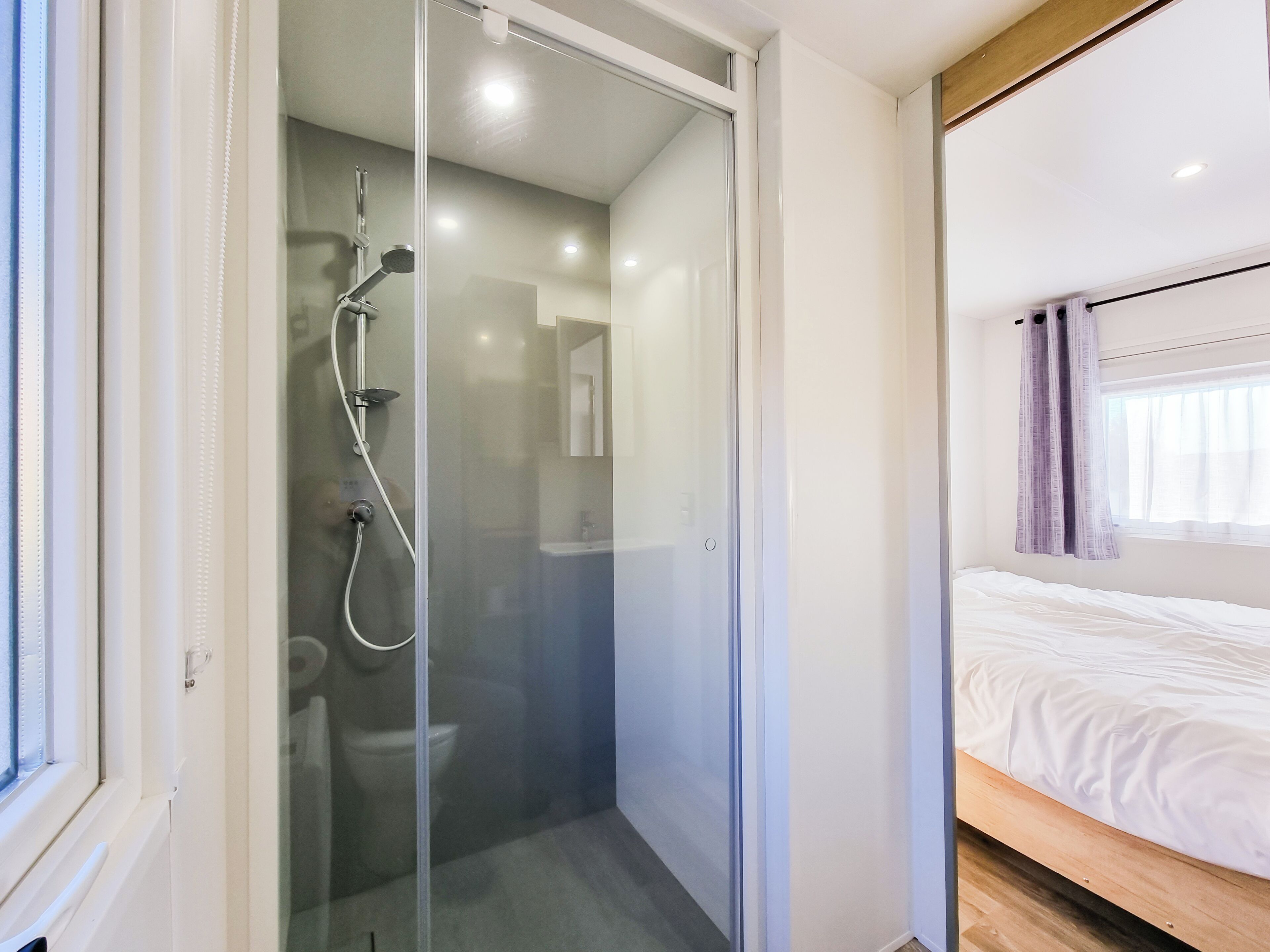 A modern bathroom with a glass-enclosed shower, a toilet, and a sink.