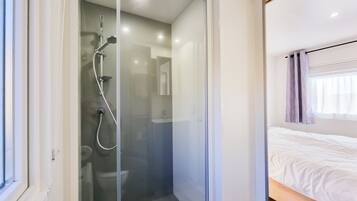 Un baño moderno con ducha envuelta en vidrio, un inodoro y un lavabo.