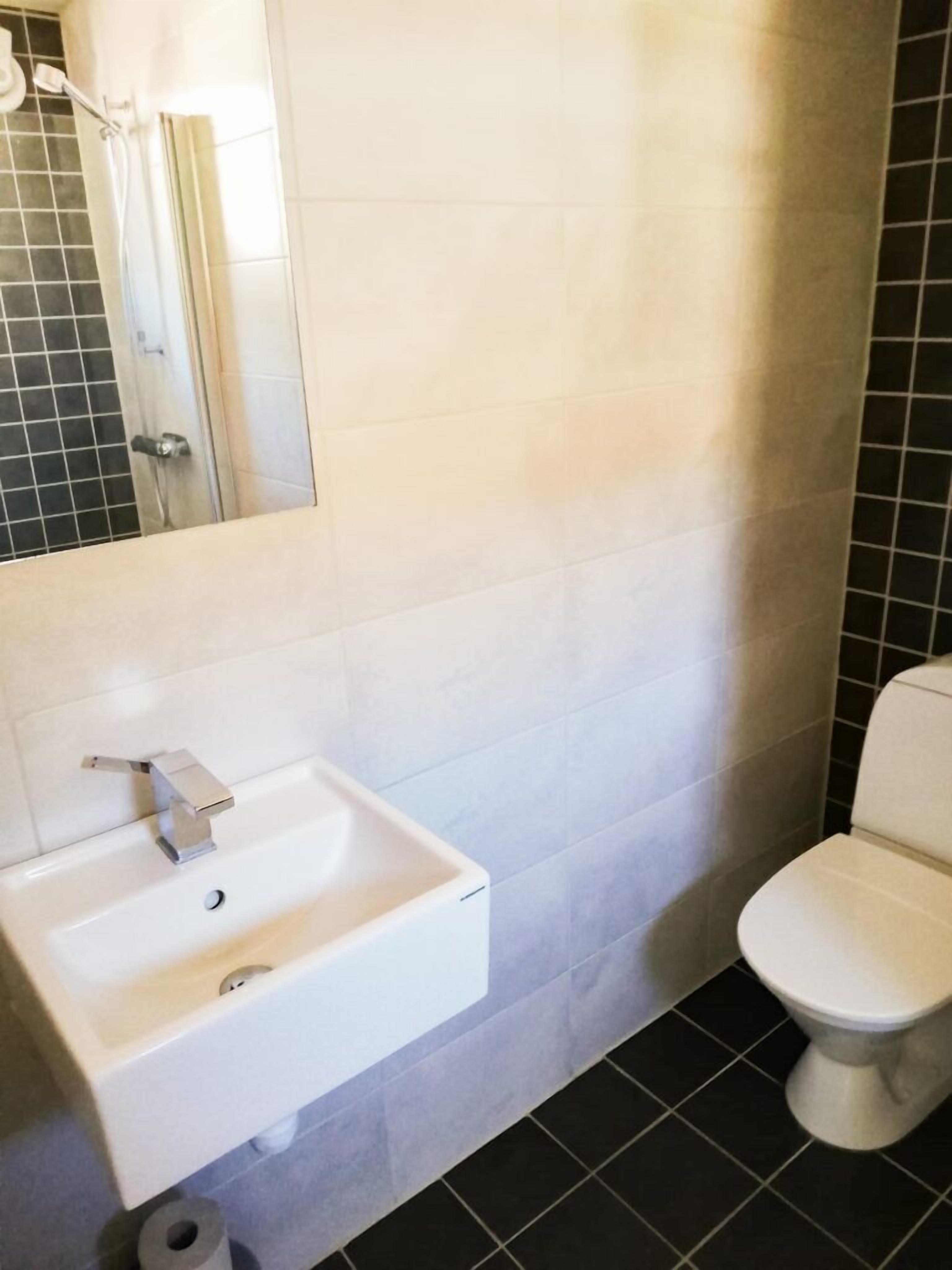 A bathroom with a white sink, a toilet, and a shower area.