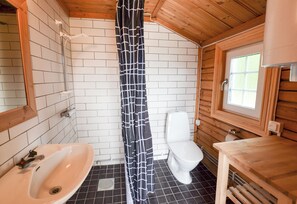 Ein Badezimmer mit Holzvertäfelung, einer weißen Toilette, einem Waschbecken und einer Duschvorhang.