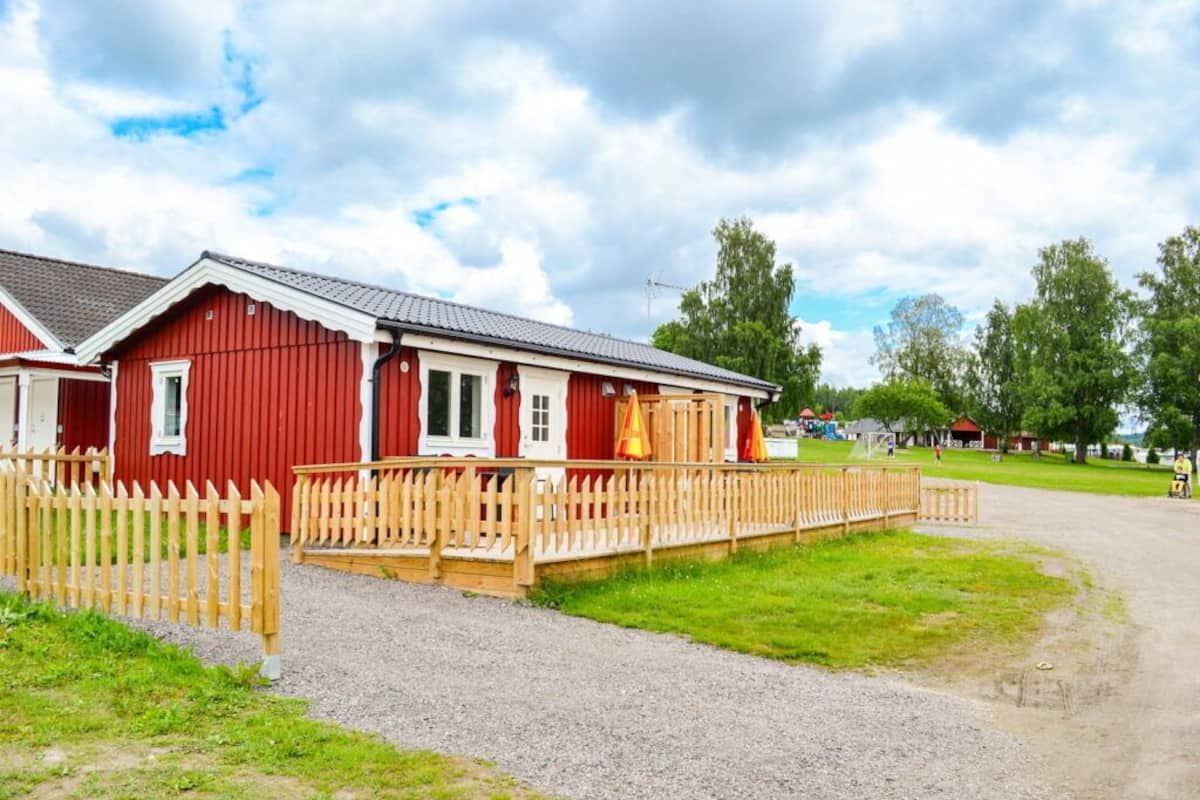 A red building with a wooden deck and a gravel path leading to it.