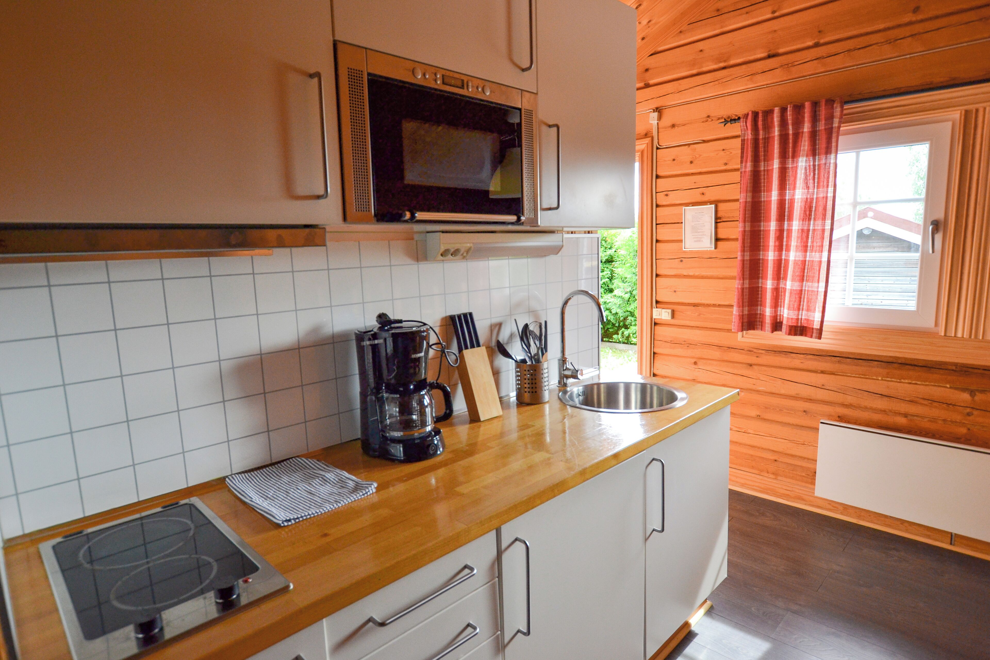 Una cocina compacta con microondas, estufa y lavabo.