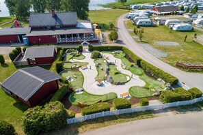 Ein Golfplatz mit Klubhaus, Wohnmobilstellplätzen und einem See im Hintergrund.