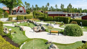Un parcours de golf avec une grange rouge et plusieurs chalets en arrière-plan.