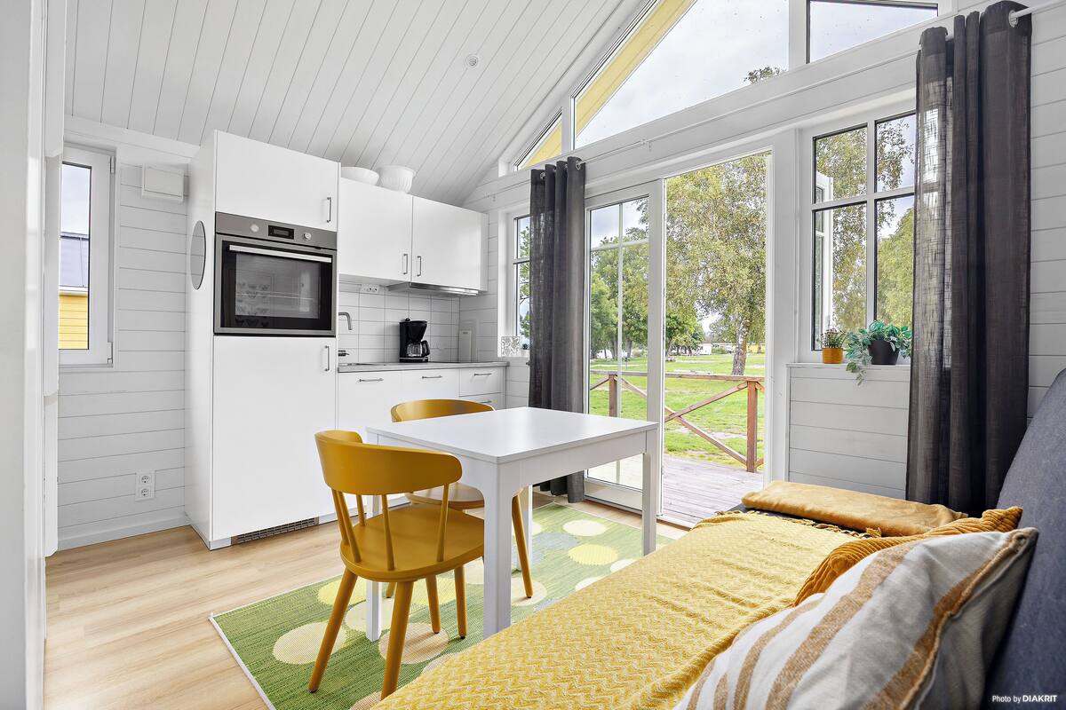 A modern kitchen with white cabinets, a built-in oven, and a dining area with a table and chairs.