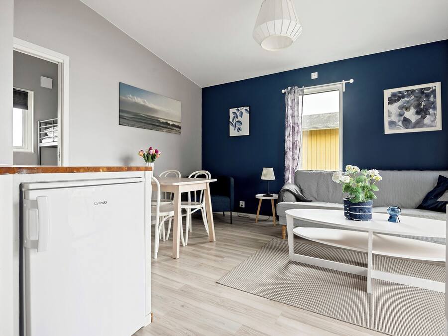 Un espace de vie compact comprenant un coin cuisine, un coin repas et un espace détente avec un canapé et une table.