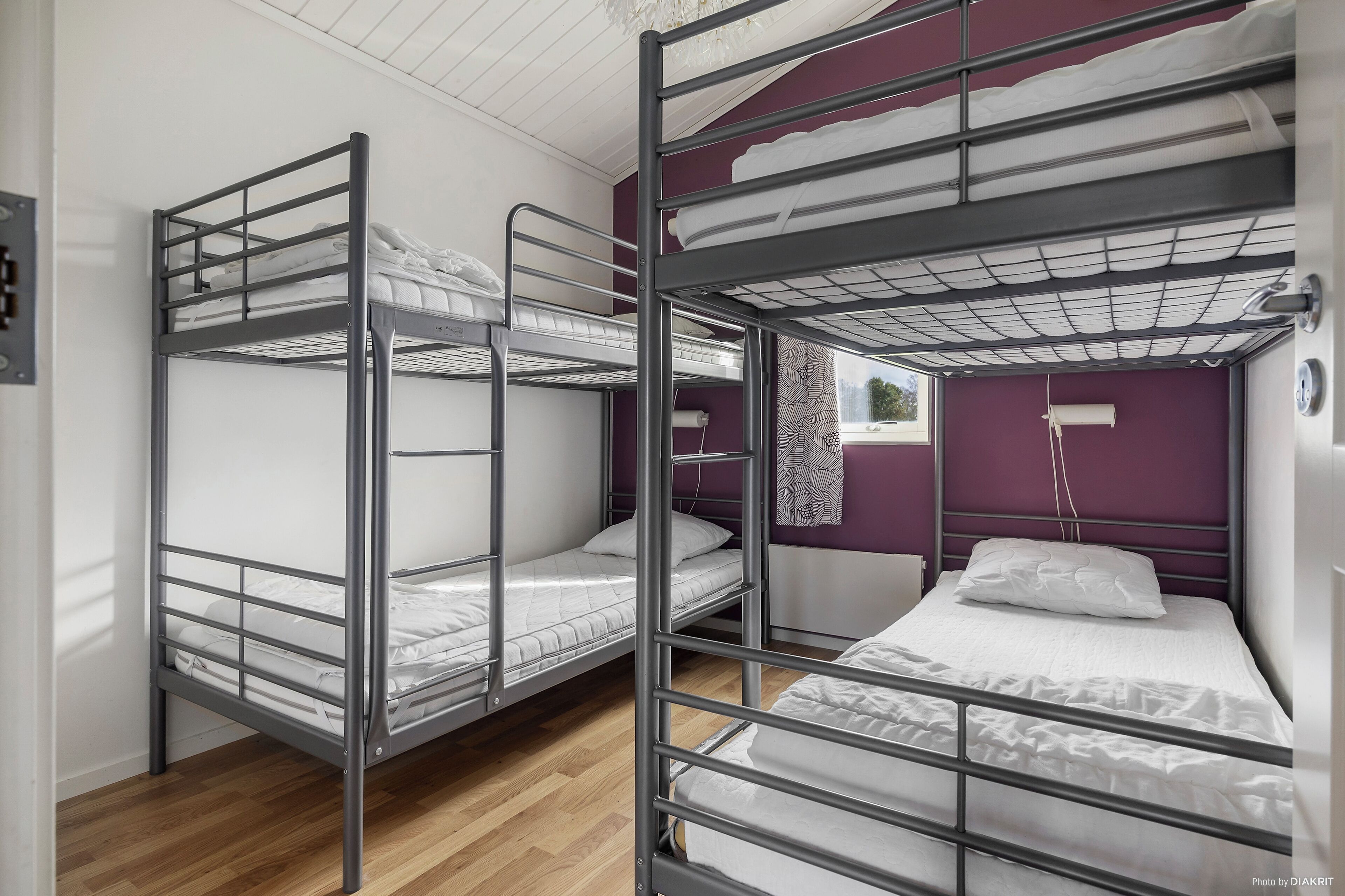 Ein Schlafsaalzimmer mit Etagenbetten, Holzboden und einer Wand in Lila.