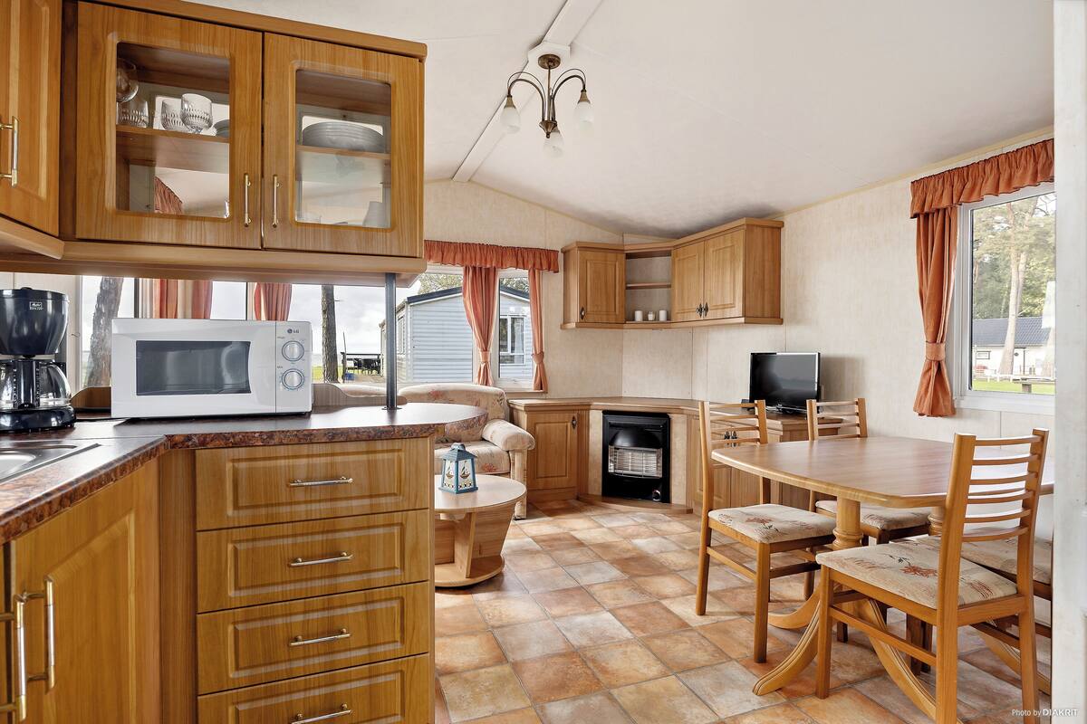 A kitchen with wooden cabinets, a microwave, a dining table with chairs, and a fireplace.