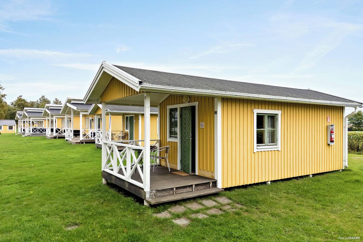 A row of yellow cabins with white railings, each with a door and a window.