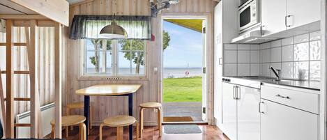 Une cuisine compacte avec vue sur la mer, des meubles en bois et un petit coin repas.