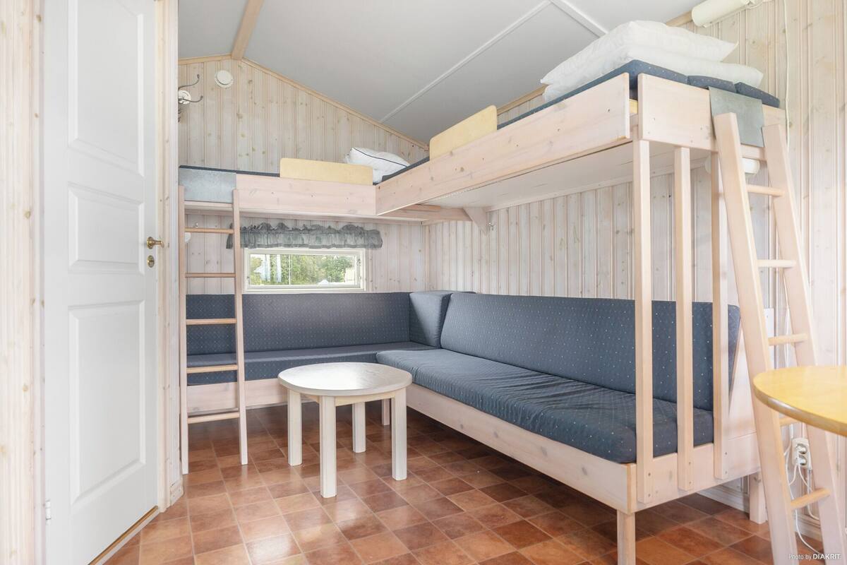 A compact room with a bunk bed, a small round table, and a sofa.