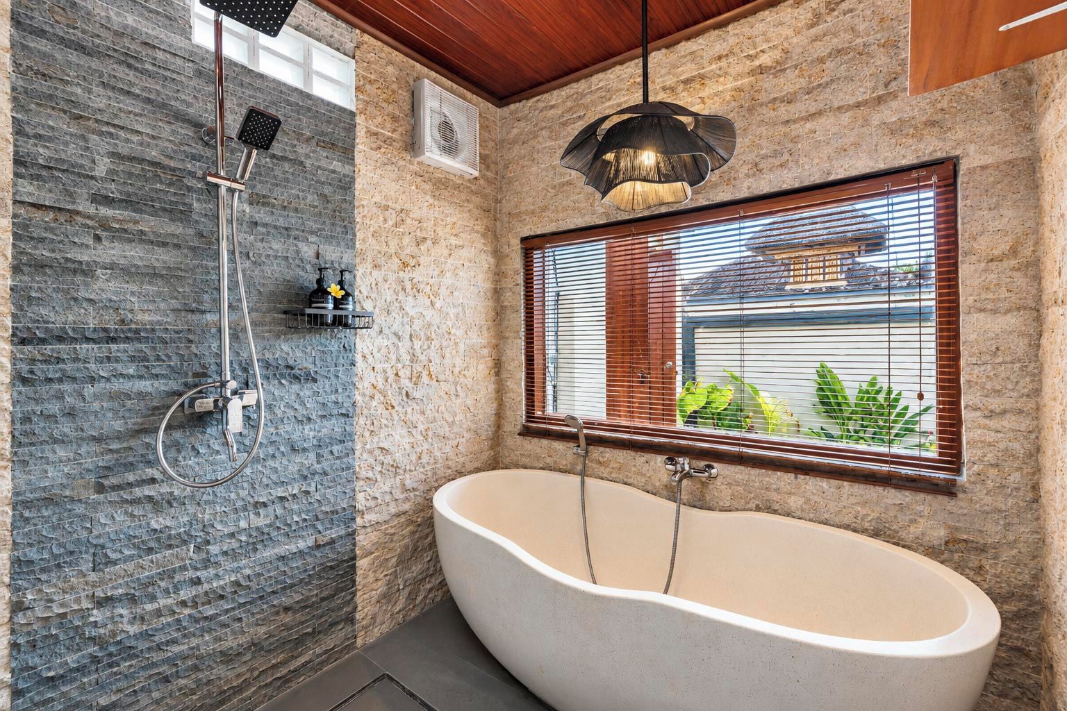 A bathroom with a freestanding bathtub, a shower with a rain showerhead, and a window with blinds.