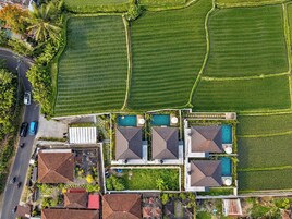 Vue aérienne d’une propriété comprenant plusieurs piscines, des champs en terrasses et des bâtiments résidentiels.