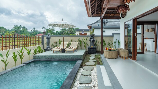 A modern outdoor pool area with lounge chairs, a statue, and a pergola. - Mahayani Ubud Villa (Tegallalang)