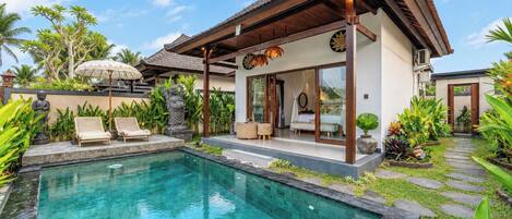 Una casa moderna con piscina, area relax esterna e piante tropicali.