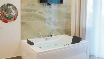 A modern bathroom with a freestanding bathtub, a mounted TV, and a large mirror.