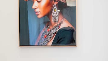 Ein gerahmtes Porträt einer Person in traditioneller Kleidung mit Schmuck, an einer weißen Wand angebracht.