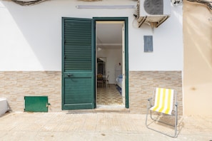 An open door leading to a room with a tiled floor, a green shuttered door, a green utility box, and a striped beach chair. - Studio 'Little Casa Giovy' with Sea View, Wi-Fi and Air Conditioning (Palermo)