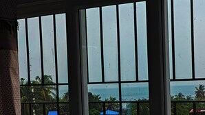 A view through a window with vertical bars, displaying a coastal area with buildings and palm trees. - Ross Harriet View (Port Blair)