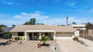 A single-story house with a front driveway, a garage, and a small front yard with landscaping. - Charming, very quiet house (Lake Havasu City)