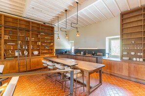 Une cuisine spacieuse avec des meubles en bois, un grand îlot central doté de tabourets et un éclairage suspendu.