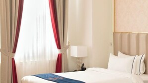 A hotel room with a bed, curtains, a lamp, and a headboard. - The Premier Palace Hotel and Spa (Phnom Penh)