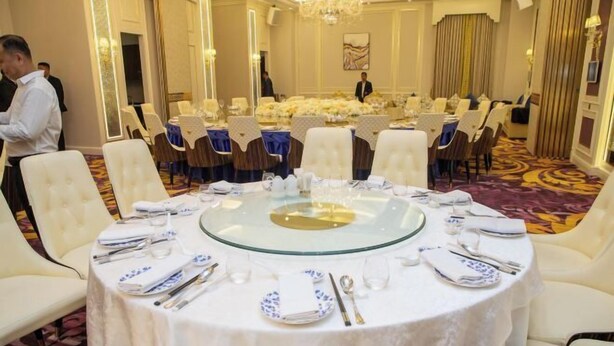 A formal dining room with round tables, white chairs, and a chandelier. - The Premier Palace Hotel and Spa (Phnom Penh)