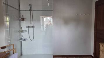 Una ducha a pie con paredes de vidrio, un banco de madera y suelo de baldosas.