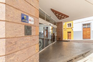 A building entrance with a stone facade, a glass door, and a sign indicating a location in Gran Canaria. - Vacation 'Las Sirenas Ii' with Wi-Fi and Air Conditioning (Las Palmas)