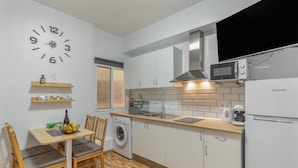 Cocina compacta equipada con lavadora, microondas y un refrigerador Brandt.