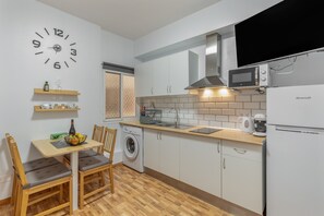A compact kitchen with a washing machine, microwave, and a Brandt refrigerator. - Vacation 'Las Sirenas Ii' with Wi-Fi and Air Conditioning (Las Palmas)