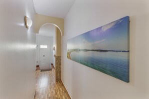 A hallway with a painting of a landscape, a door, and a light fixture. - Vacation 'Las Sirenas Ii' with Wi-Fi and Air Conditioning (Las Palmas)