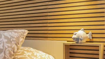 Ein Zimmer mit einem Holzlamellen-Kopfteil, einem dekorativen Fischornament und gemustertem Bettzeug.