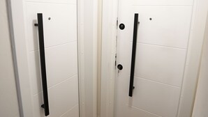 A hallway with two white doors, each with a black handle, and a brown doormat at the entrance. - Huqi Luxury Apartments (Tirana)