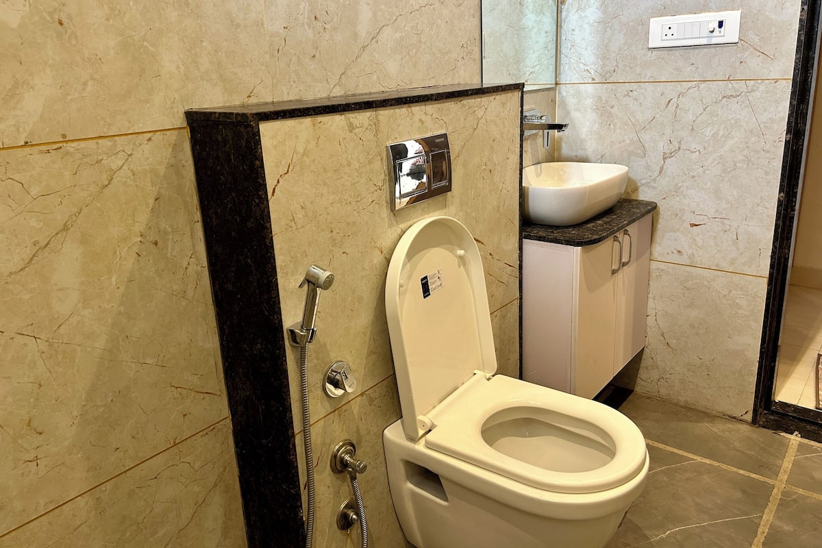 A modern bathroom with a toilet, a shower, and a sink.