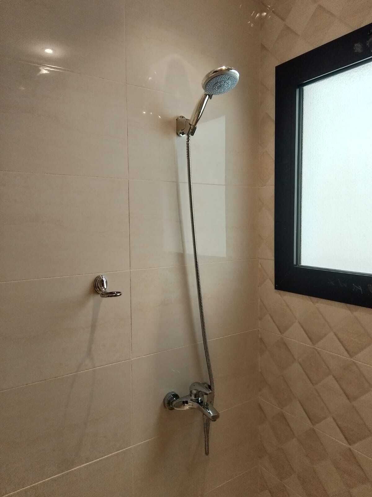 Ein Badezimmer mit Dusche, Tür und Fenster.