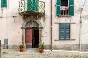 Un bâtiment doté d’une porte en bois, de volets verts et d’un balcon orné de ferronnerie décorative.