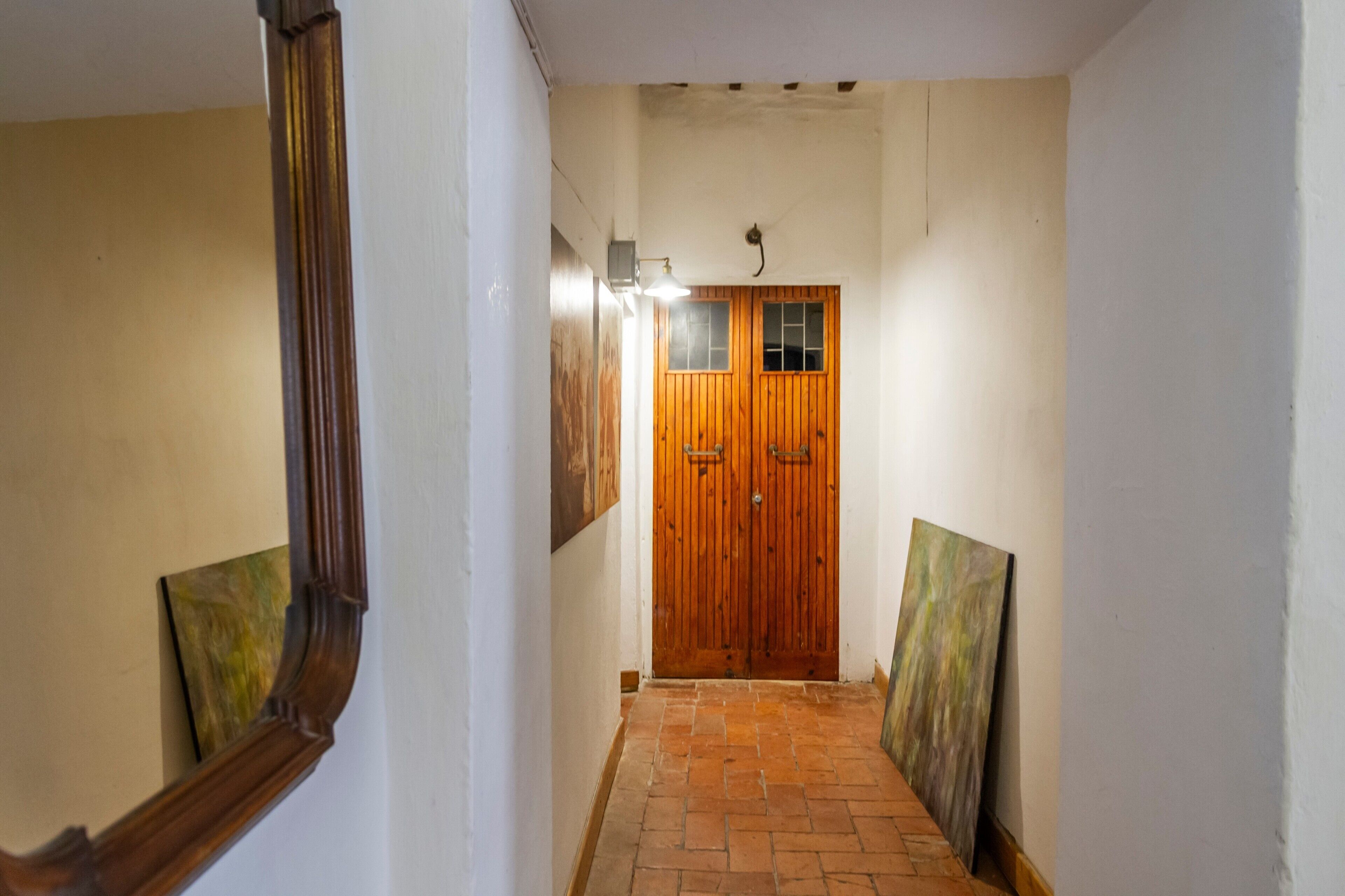 A hallway with a wooden door, a light fixture, and a mirror.