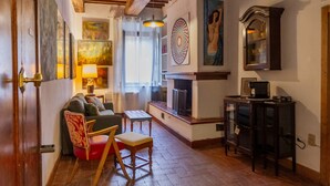 Ein Wohnzimmer mit einer Couch, einem Sessel, einem Tisch, einem Kamin und einem Schrank.