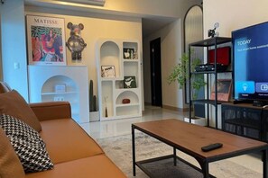 Una sala de estar con un sofá, una mesa de centro, un televisor y una estantería.